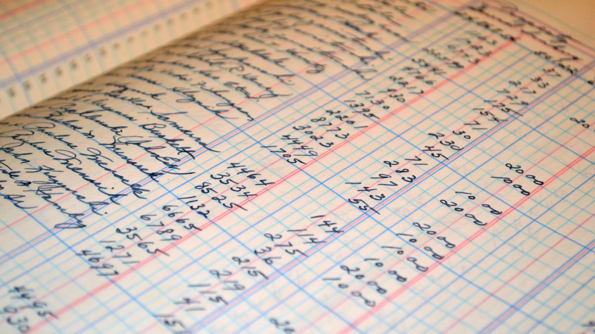 An open accounts book filled with columns of handwritten figures, ruled in red and blue.