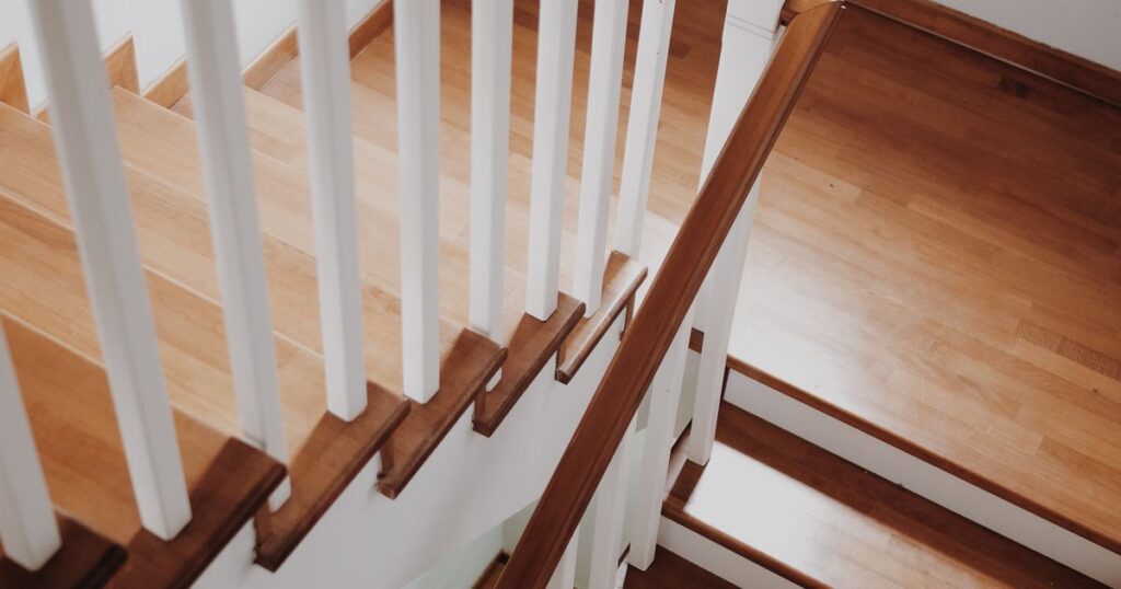 A wooden staircase with white balusters seen from above in a pale interior