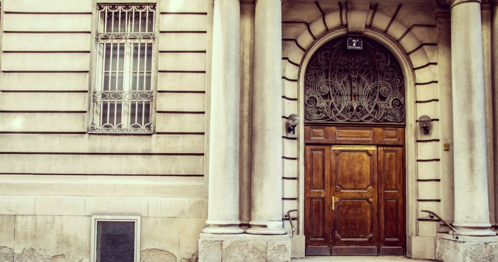 Closed wooden street door set in a pale stone entrance with columns on either side