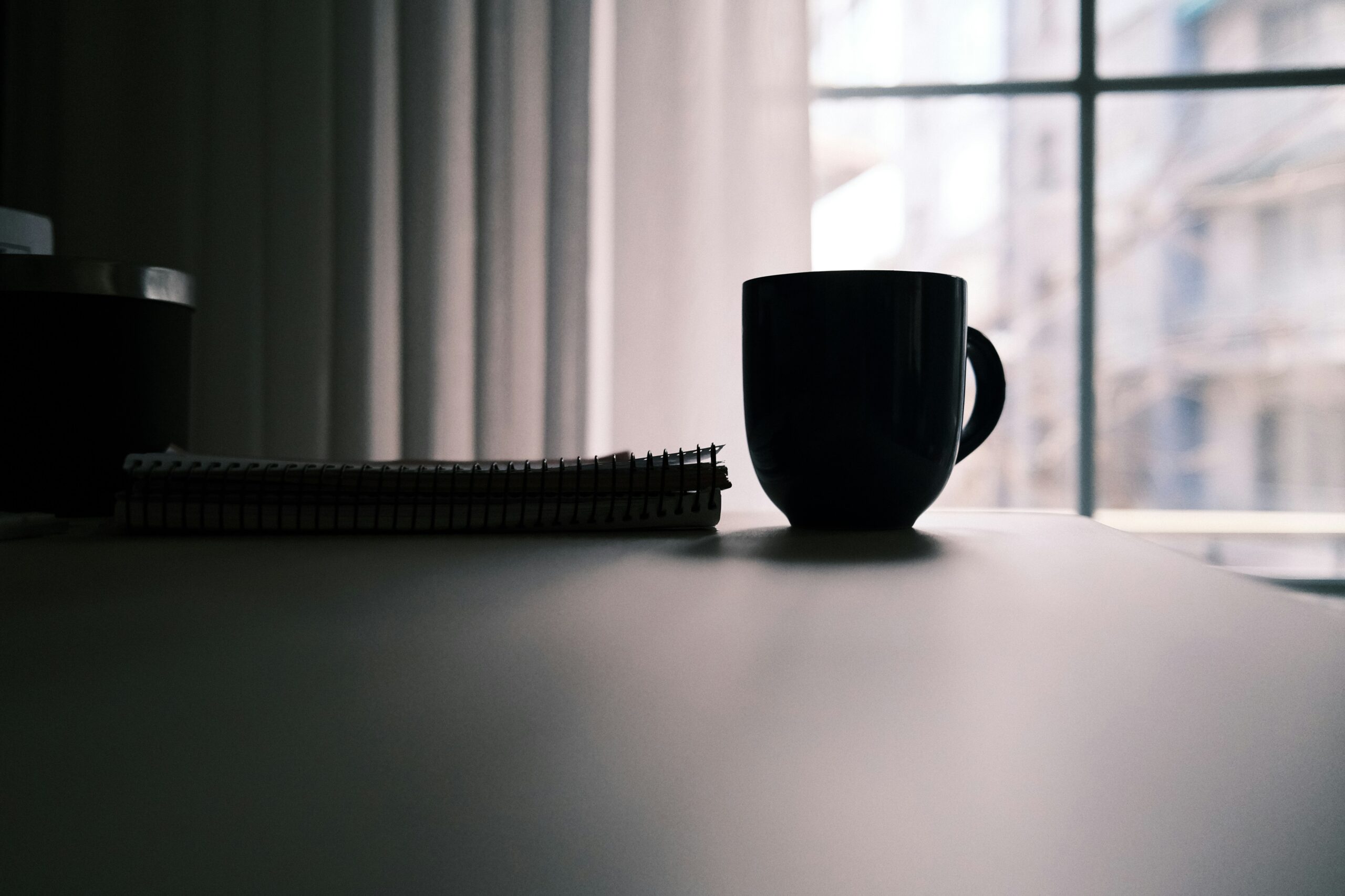 A blue ceramic mug standing alone on a white table in soft daylight