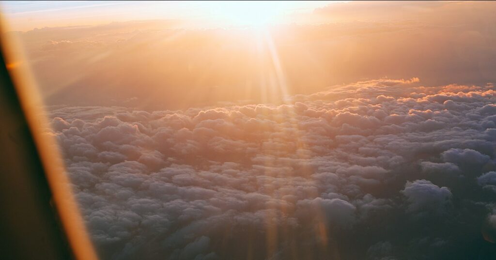 Sunrise over a field of cloud seen past the frame of an aeroplane window