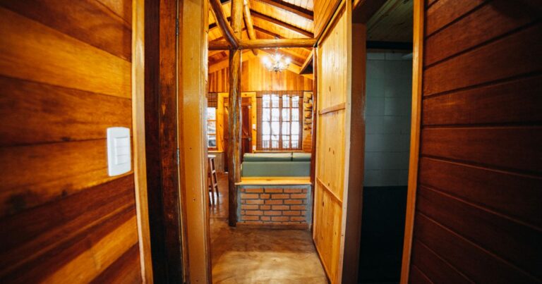 A wooden hallway in a cabin with closed wooden doors and warm daylight