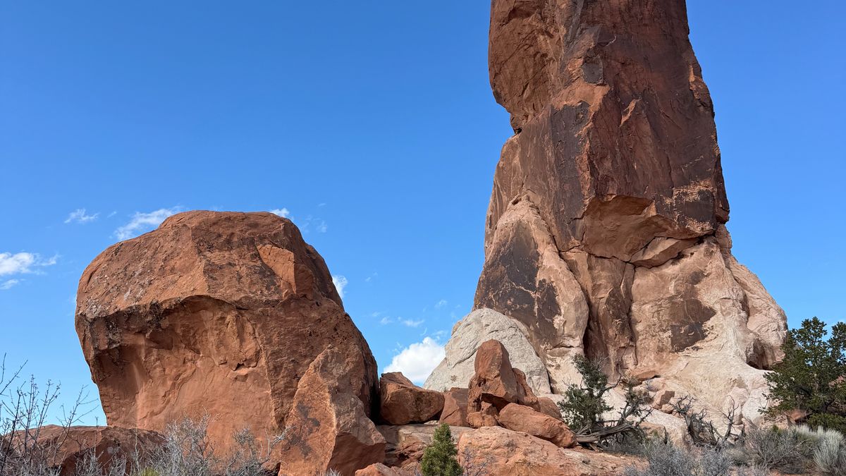 A tall red sandstone tower and a rounded boulder standing side by side