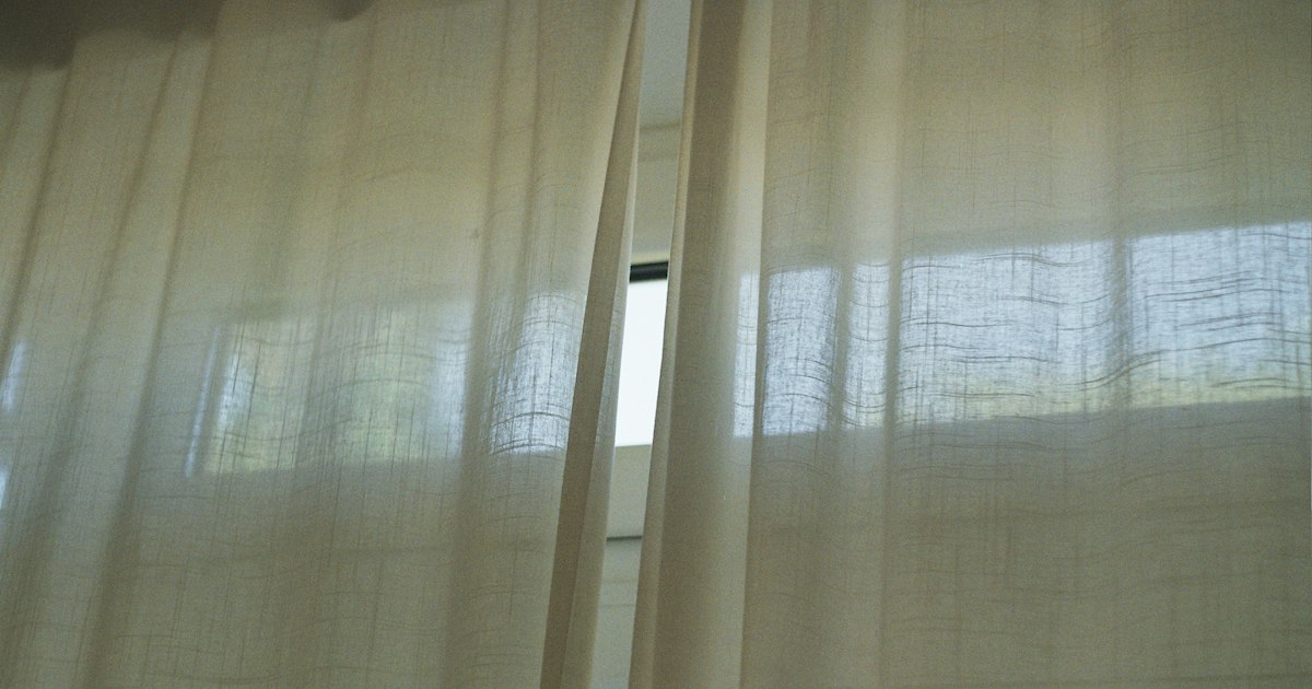 Two pale curtains with a narrow gap of daylight between them