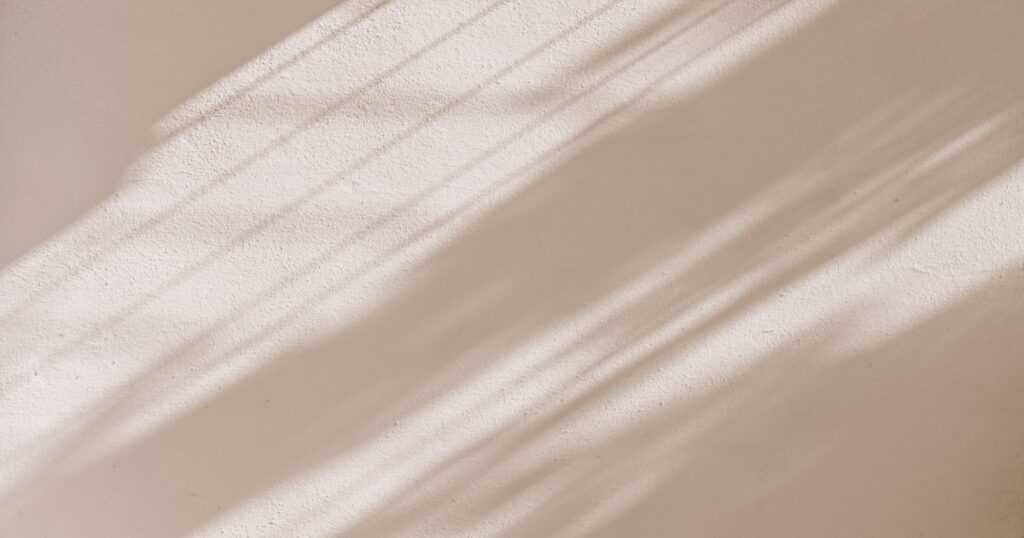Soft diagonal daylight falling across a plain beige wall