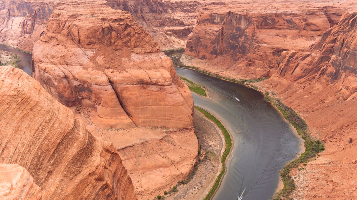 A wide river curving around a great block of red rock, passing on both sides