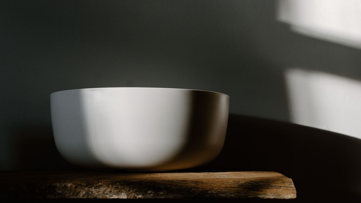 A plain white bowl on a wooden board in quiet daylight