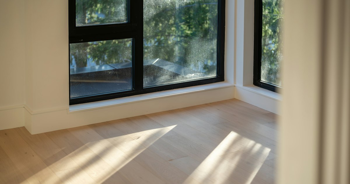 Morning sunlight falling across pale wooden floorboards beside a window