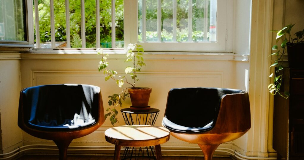 Two low chairs beside a bright window, turned slightly away from each other