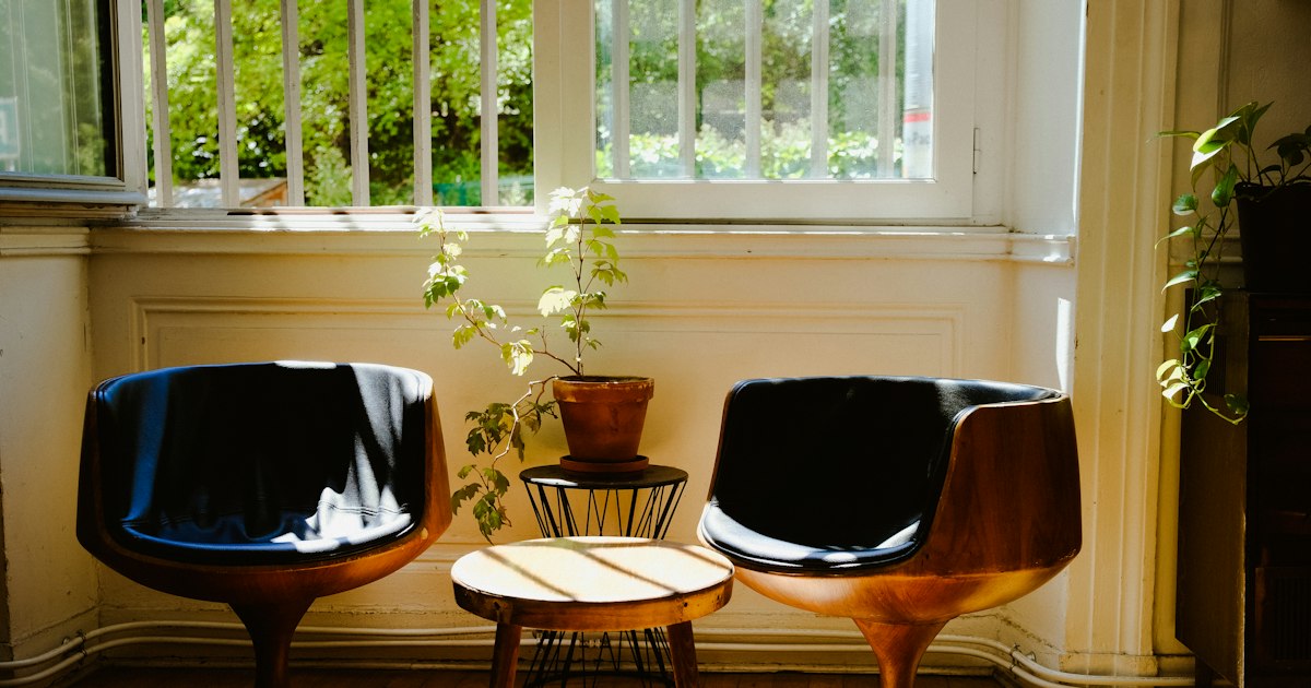 Two low chairs beside a bright window, turned slightly away from each other