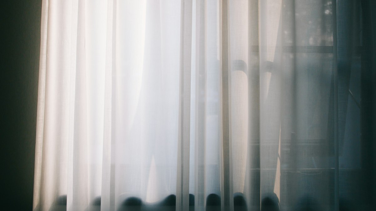 Daylight coming through a plain white curtain in a quiet room