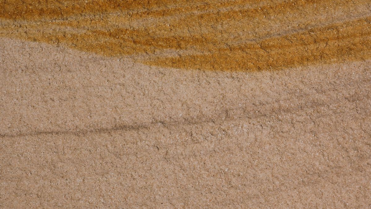 Close view of layered sandstone, a band of ochre lying over paler stone