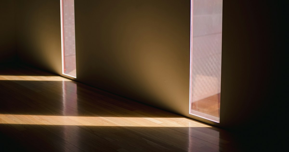 Warm daylight falling through 2 narrow doorways onto a wooden floor in a quiet room