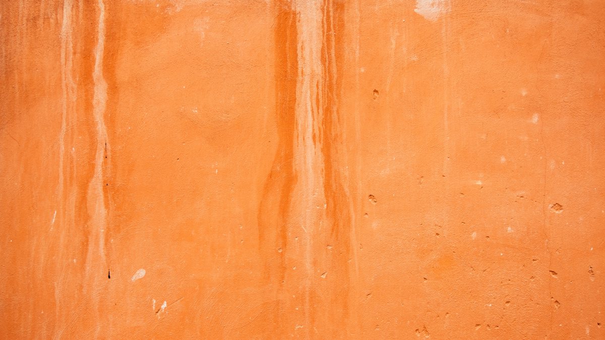 An orange plaster wall with faint marks running down it