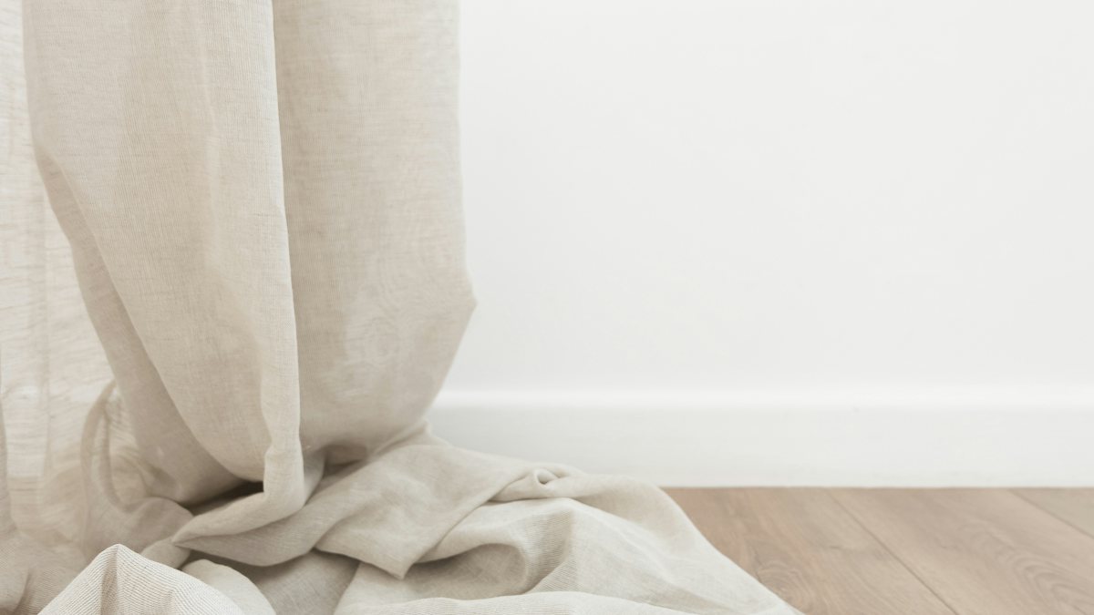 Pale linen hanging straight from above and gathered into folds where it reaches the floor