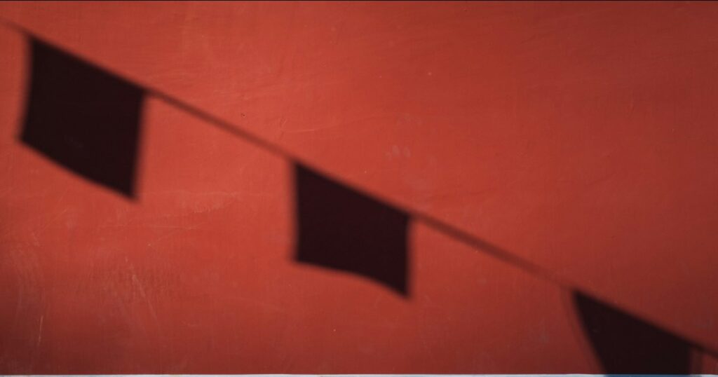 The shadow of a line of bunting falling across a deep red wall