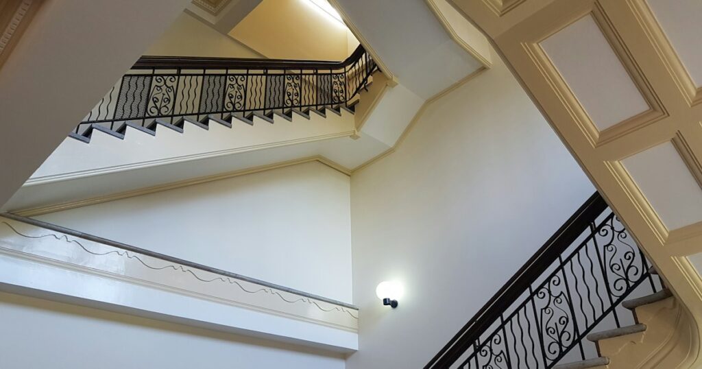 A pale stairwell seen from below, with flights of stairs turning away above each other