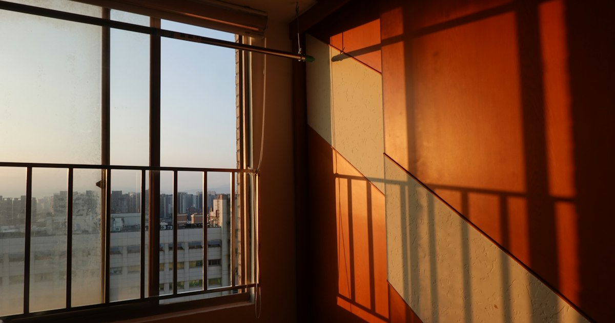 Late afternoon sunlight falling across an interior wall beside an open window