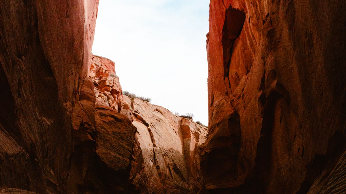 Two red sandstone walls standing apart with a band of pale sky between them