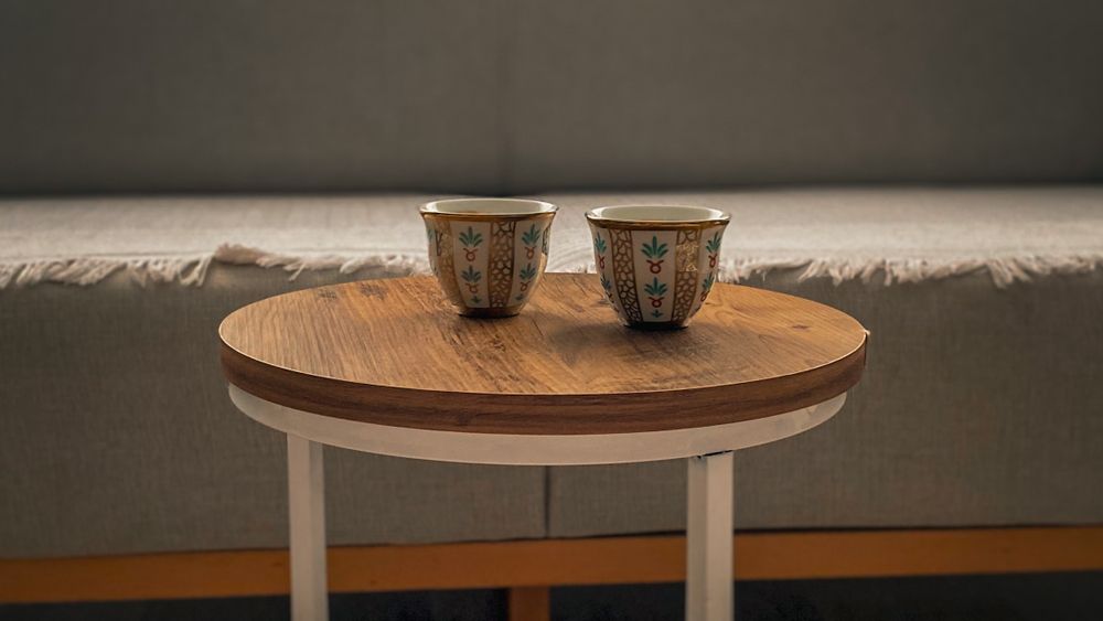 Two plain ceramic cups on a round wooden coffee table in a quiet living room