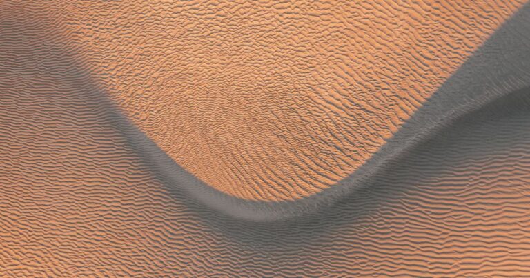 Two rippled sand ridges meeting in warm low light