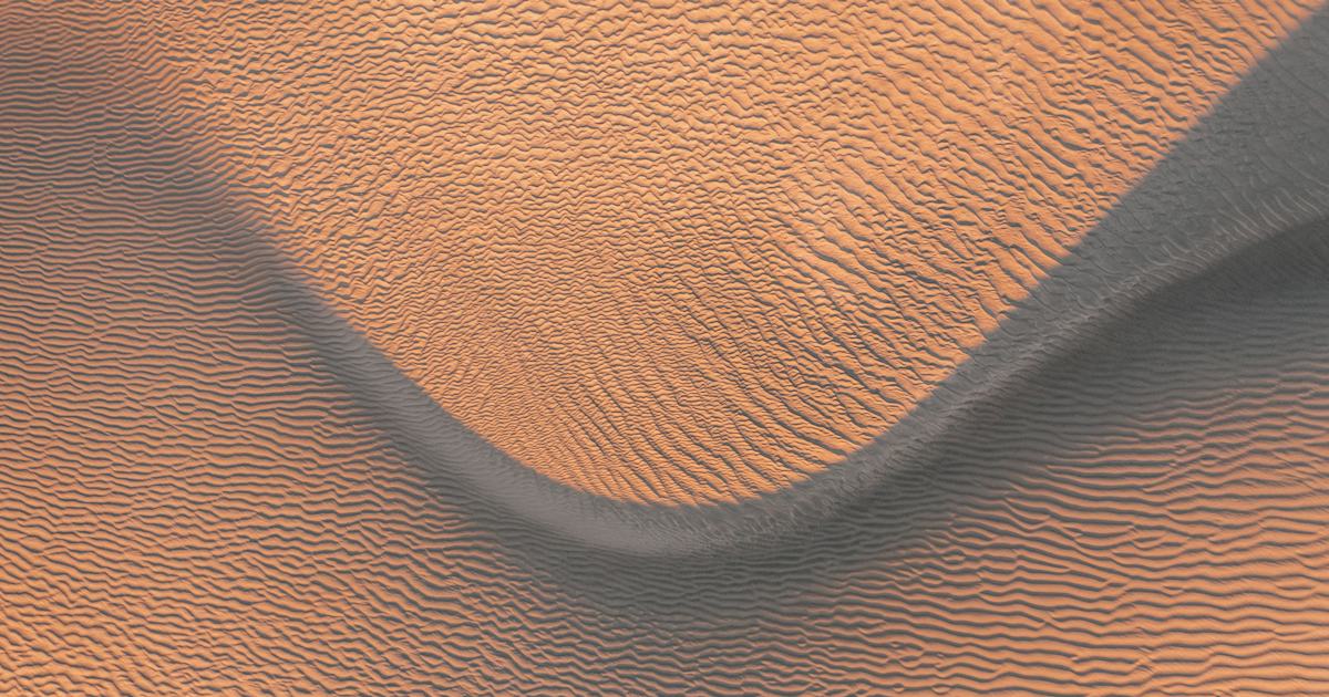 Two rippled sand ridges meeting in warm low light