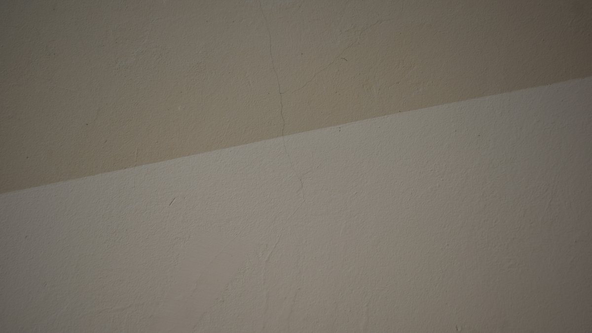 A plastered wall in 2 shades of cream, divided by a single straight line