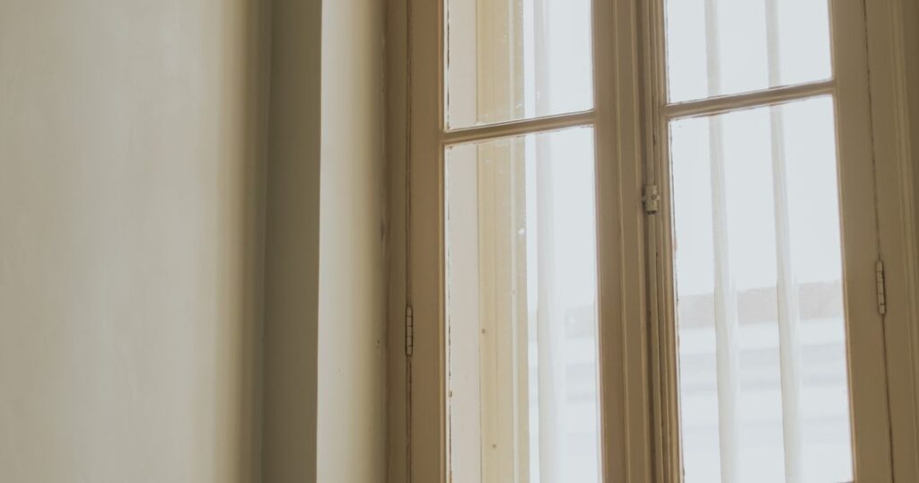 Pale morning light through a tall old window in an empty room