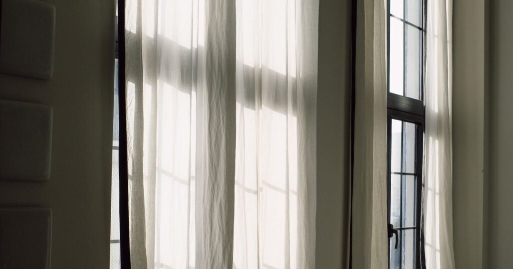 Daylight coming through sheer curtains at a tall window
