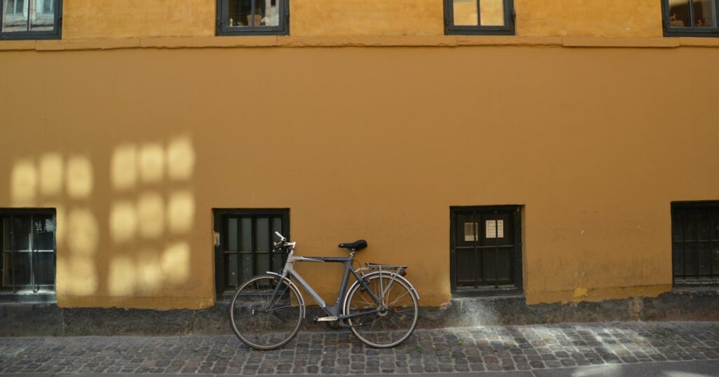 A bicycle leaning against an ochre painted wall above cobblestones